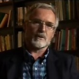 Ton Derksen zittend voor boekenkast